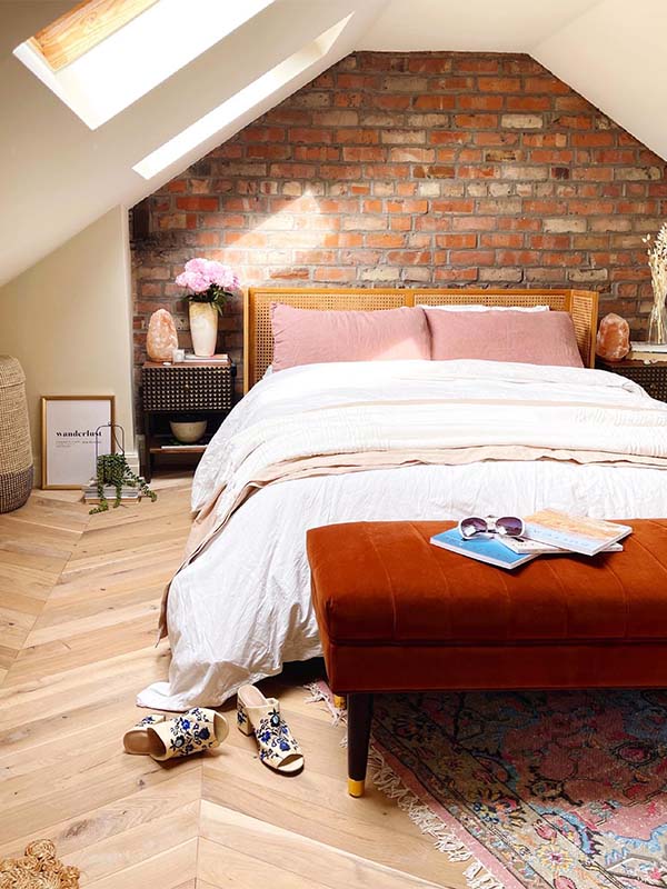 bedroom with open brick wall, herringbone floor, white bed and apricot coloured interior