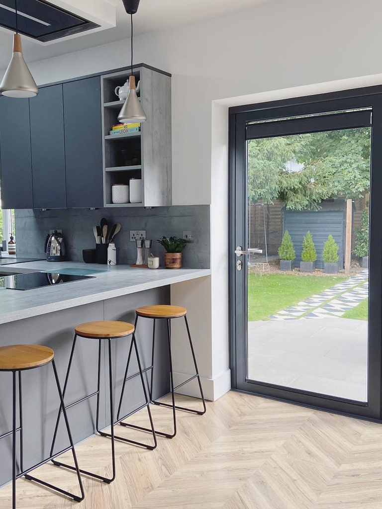 Modern kitchen with breakfast bar and light chevron flooring with patio door