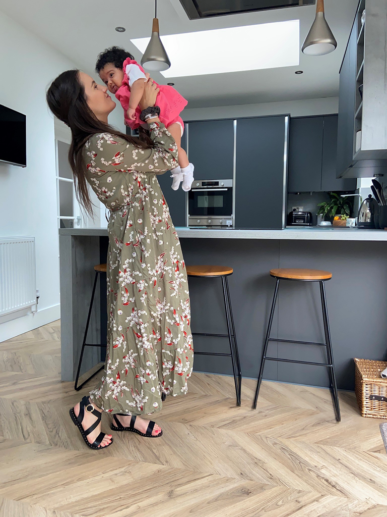 Mum holding baby in modern kitchen wearing bold maxi dress