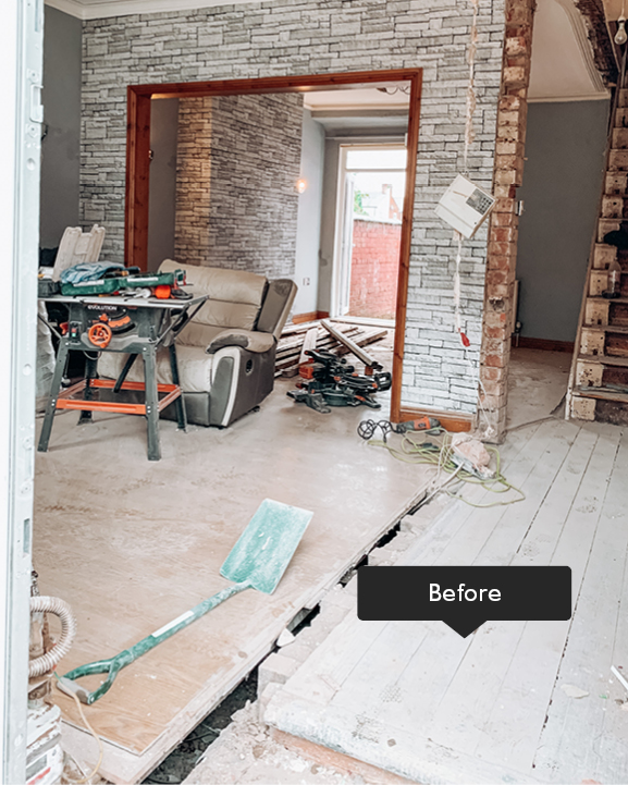 Room before renovation with floorboards and exposed brick
