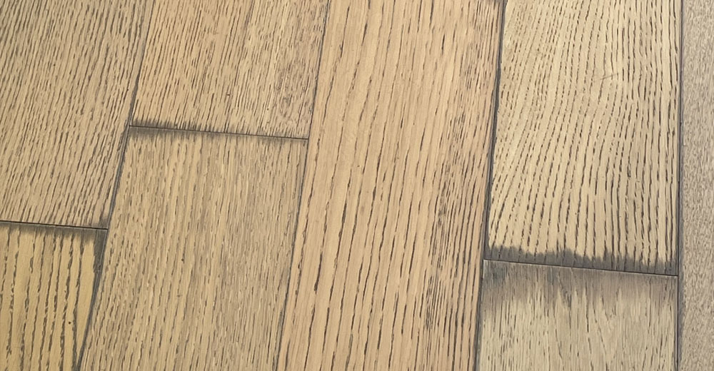 Dark water damage stains on wood floor